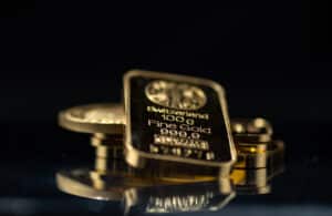 Gold bars and gold coins on a black background. Selective focus.