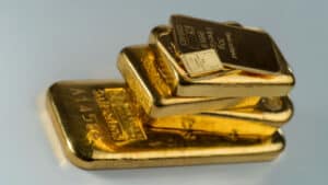 Several cast and minted gold bars on a gray background. Selective focus.